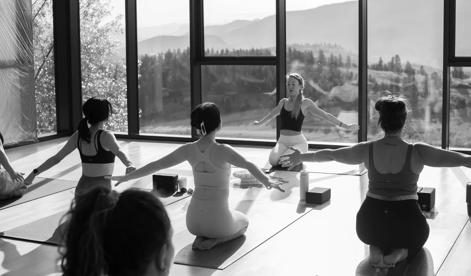 A yoga group practising in a sunlit room overlooking the hills